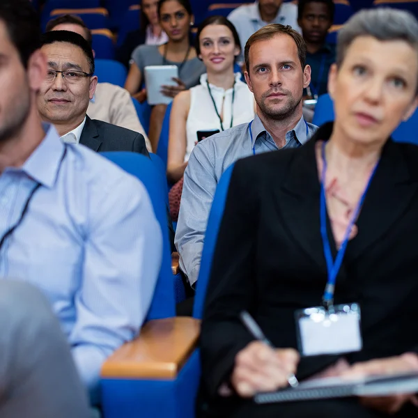 Un groupe de personnes assises dans une salle de conférence, participant à l'organisation d'un congrès.