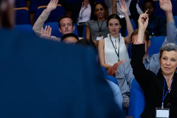Une femme lève la main devant un groupe de personnes lors d'un congrès.