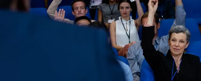 Une femme lève la main devant un groupe de personnes lors d'un congrès.
