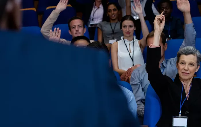 Une femme lève la main devant un groupe de personnes lors d'un congrès.